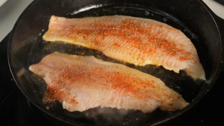 Two Seasoned Fish Fillets Are Sizzling in A Cast-Iron Skillet, Releasing a Strong Fish Smell While Cooking