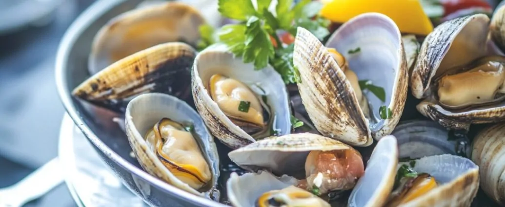 Close-up of a dish of steamed clams garnished with parsley and lemon slices