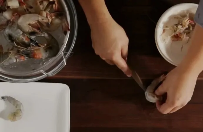 Hands deveining shrimp with a knife, showing how to devein shrimp