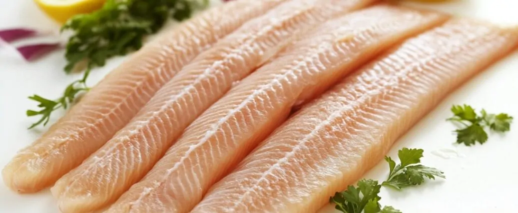 Four raw fish fillets arranged on a plate with lemon slices and parsley, illustrating the appearance of fresh seafood