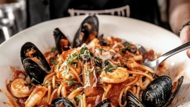 Mixed seafood pasta with shrimp, mussels, and tomato sauce in a white bowl