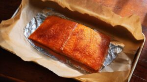 A brined salmon fillet on foil and parchment paper, prepped for smoking