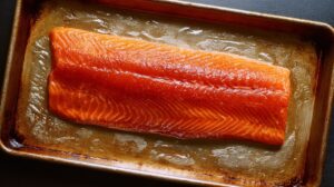 Brined salmon fillet resting on a metal baking sheet, ready for drying before smoking